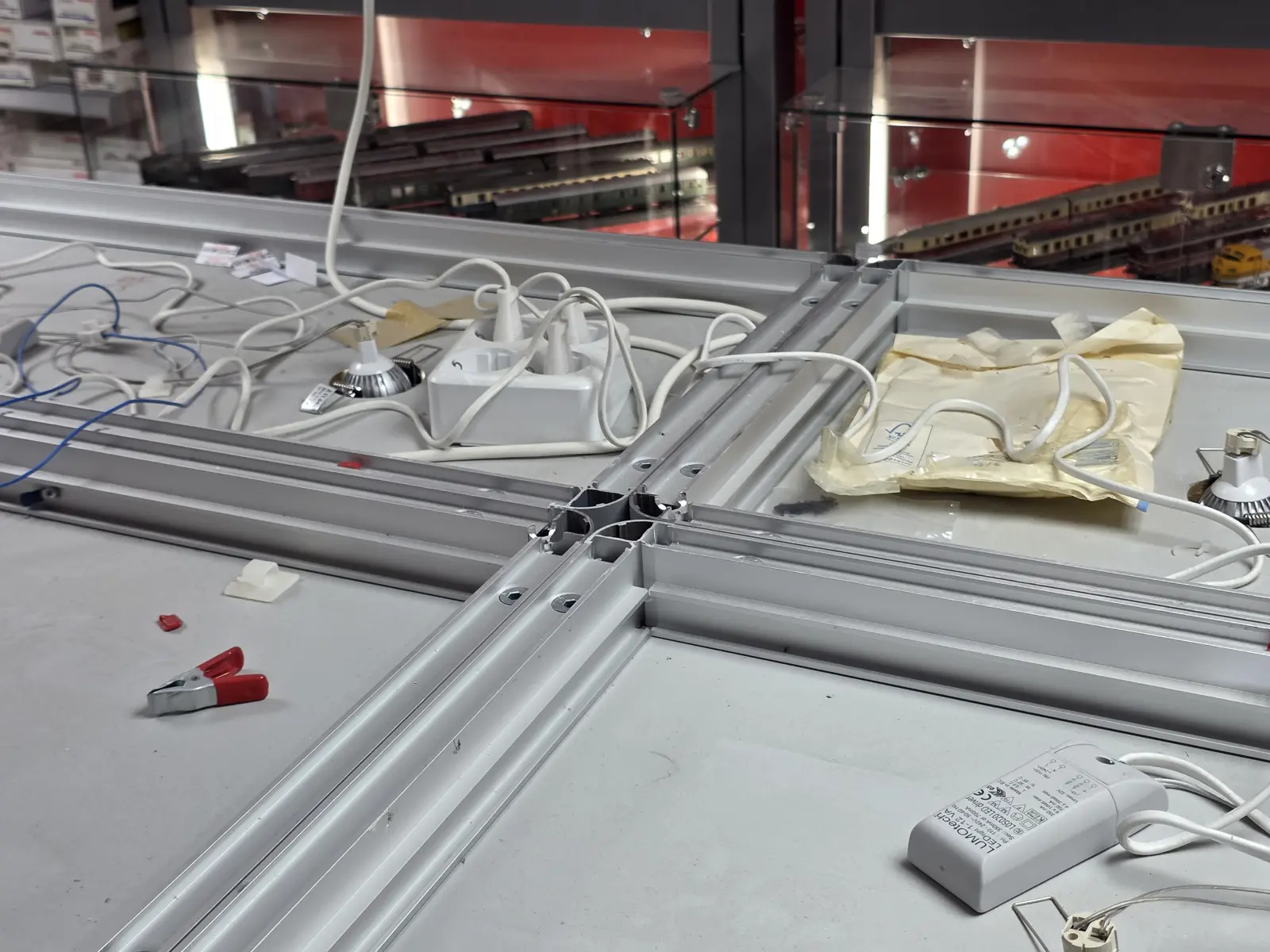 Stekkerdoos met voedingen boven een systeemplafond naast winkelvitrines